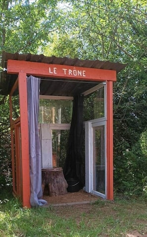 A small, enclosed structure with a red frame and a sign reading 'LE TRONE' at the entrance.
