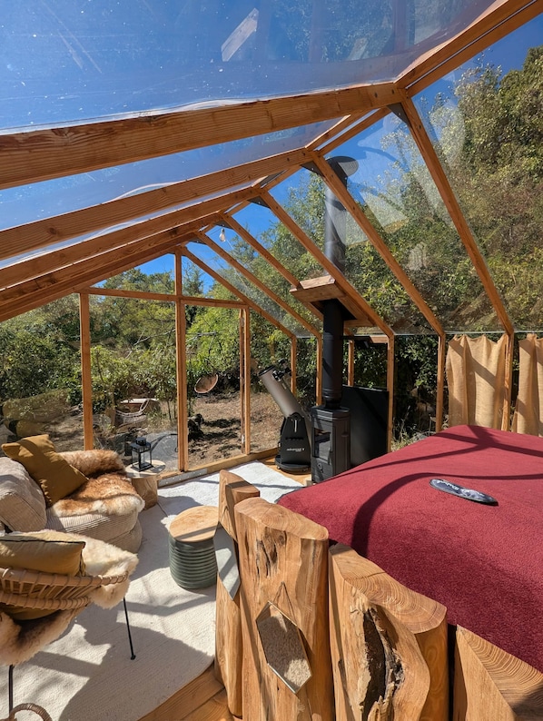 Une structure en bois abritant un télescope, un espace recouvert d’un tapis rouge et une table en bois rustique.