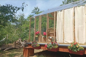 A greenhouse structure with a wooden frame, a glass enclosure, and a chair inside.