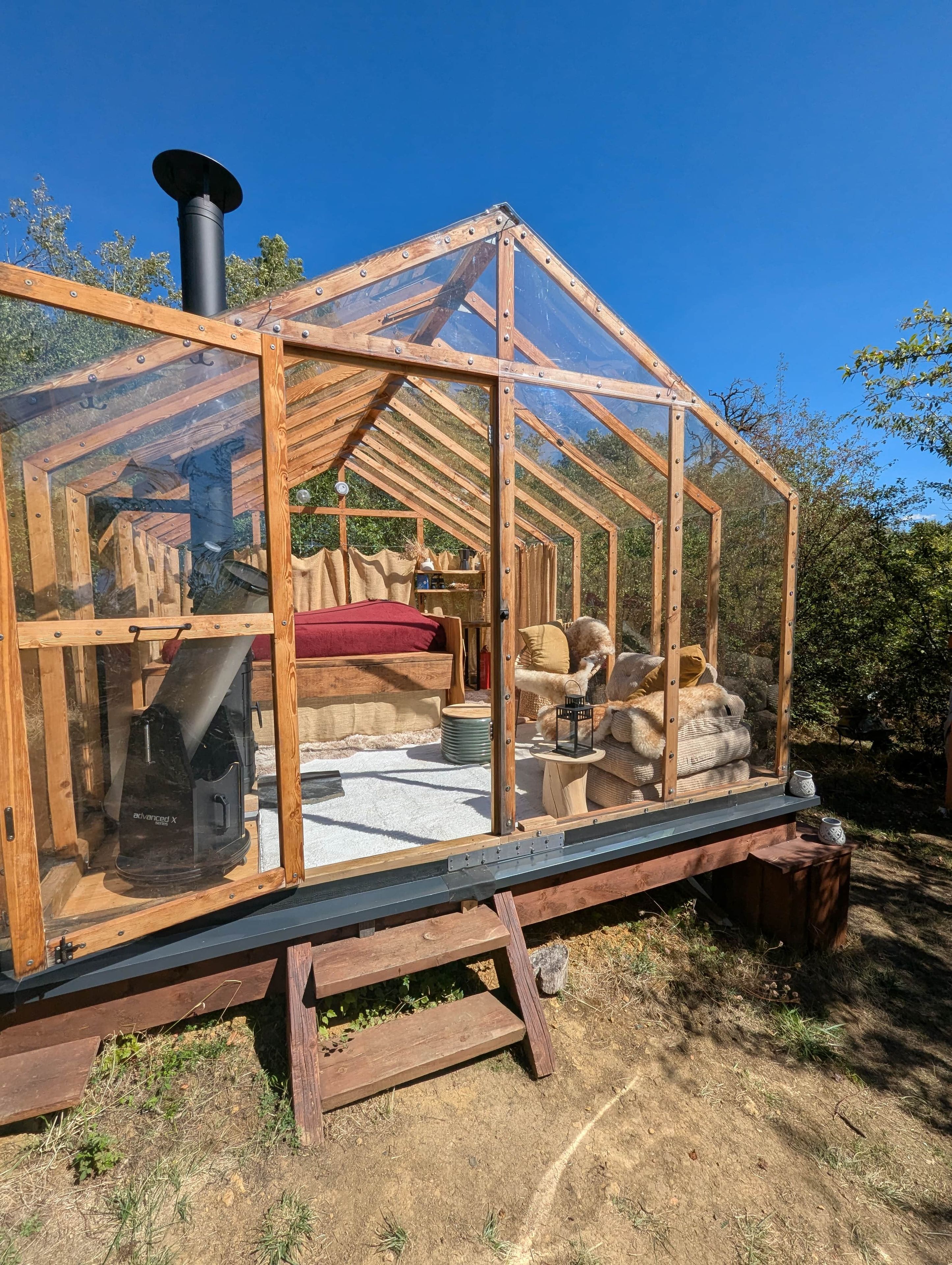 A wooden structure with a glass enclosure, a bed, a heater, and storage bins.