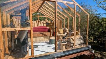 A wooden structure with a glass enclosure, a bed, a heater, and storage bins.