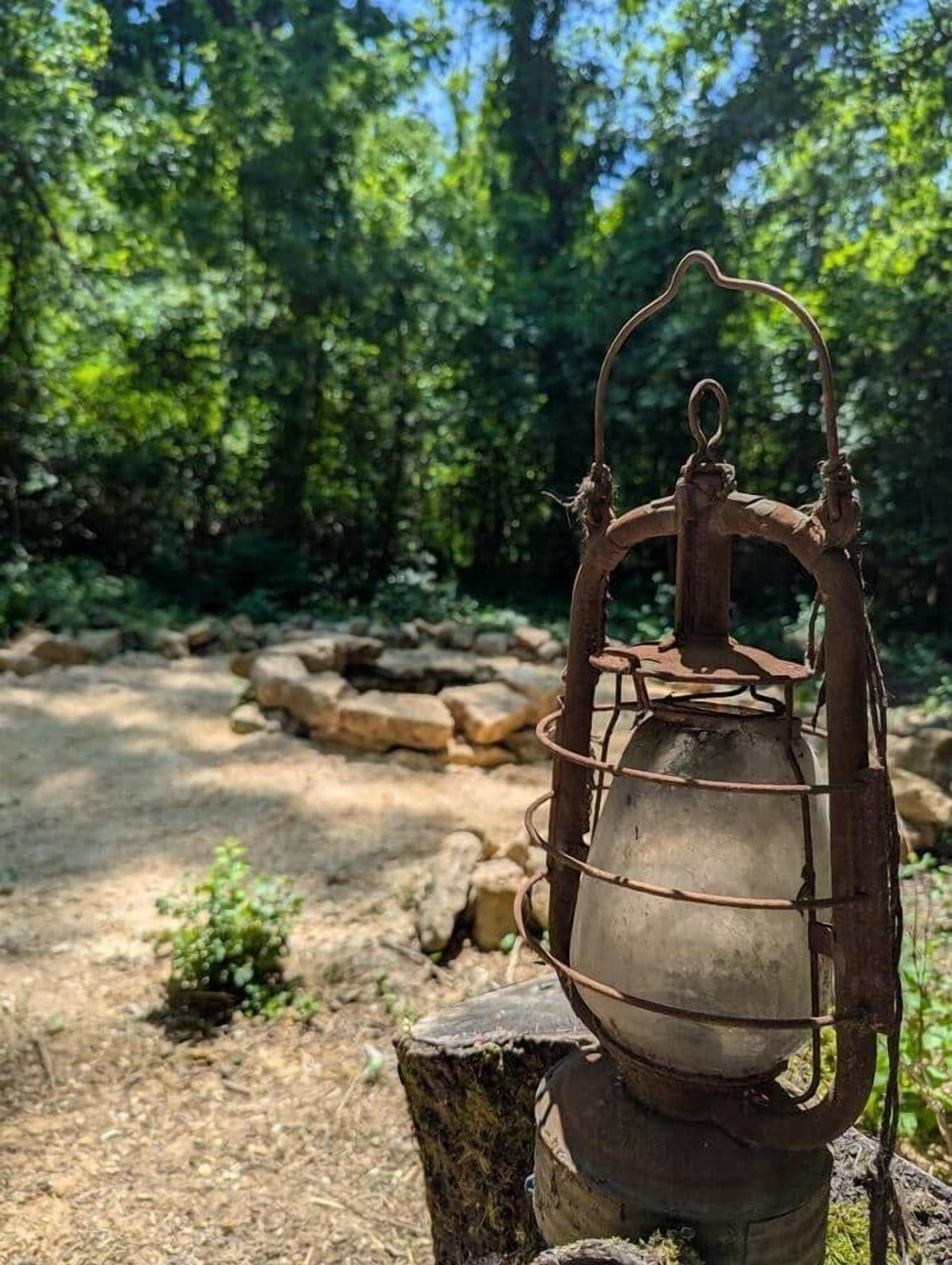 A rustic lantern on a wooden post in a forested area.