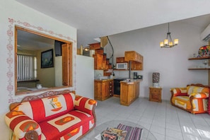 Ein Wohnzimmer mit einer Couch, einem Couchtisch und einem Essbereich mit Holzschränken und einer Mikrowelle.
