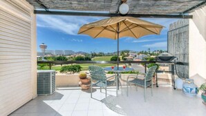 En overdækket terrasse med et bord, stole og en parasol.