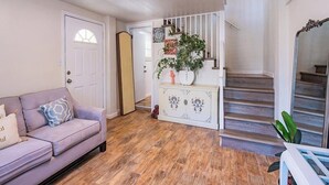 Ein Wohnzimmer mit einer Couch, einem Schrank mit Dekoration, einer Treppe und einer Tür zu einem weiteren Raum.