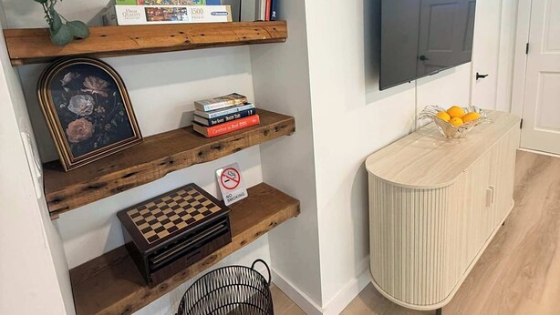 Un salon avec des étagères en bois, un téléviseur, un jeu d’échecs et un panneau indiquant « Il est interdit de fumer ».