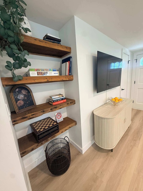 Una sala de estar con estanterías de madera, un televisor, un tablero de ajedrez y un cartel de 'No Fumar'.