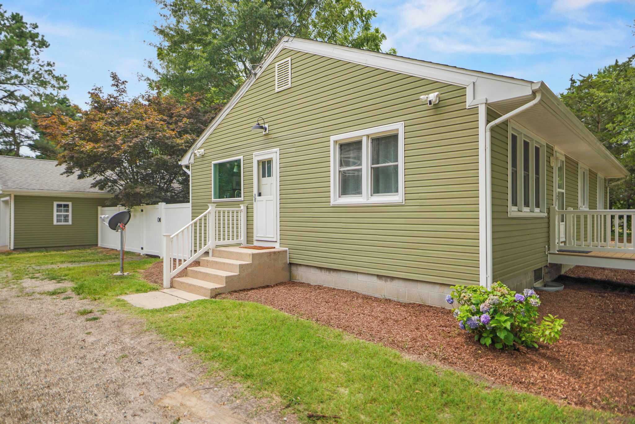 A single-story house with a front porch, a small front yard, and a satellite dish.
