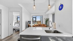 A modern kitchen with a central island, stainless steel sink, and pendant lighting. - 2-bedroom Boutique Suite in SoWa Boston (Boston)