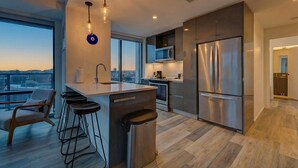 A modern kitchen with a large island, stainless steel appliances, and a city view. - 2-bedroom Boutique Suite in SoWa Boston (Boston)