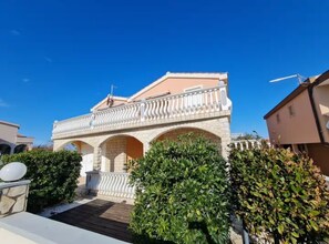 A building with a balcony, stone arches, and a clear blue sky. - Villa Ana (Vir)