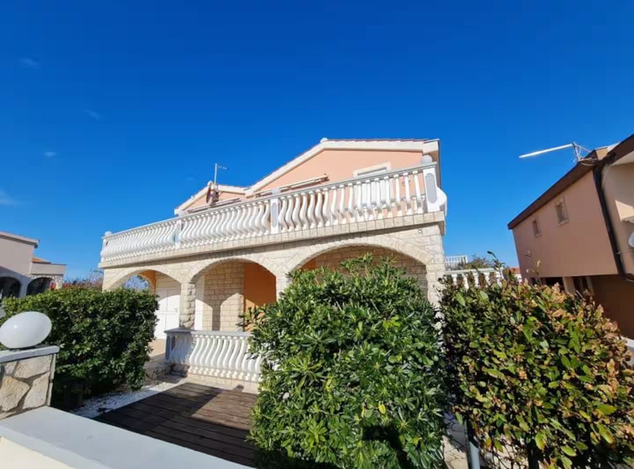 A building with a balcony, stone arches, and a clear blue sky.