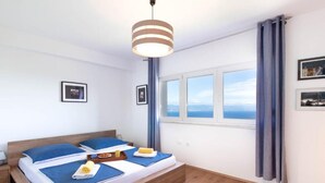 Een slaapkamer met een houten bed, een nachtkastje, een raam met uitzicht en een hanglamp.