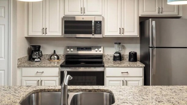 A modern kitchen with white cabinets, a stainless steel refrigerator, a microwave, a stove, a coffee maker, and a blender. - 2 bedroom condo at Holiday Inn Vacation Club Orange Lake Resort in Kissimmee, FL (Kissimmee)