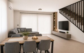 A modern living room with a sofa, dining table, chairs, a TV, and a staircase. - Beautiful home in Privlaka (Privlaka)