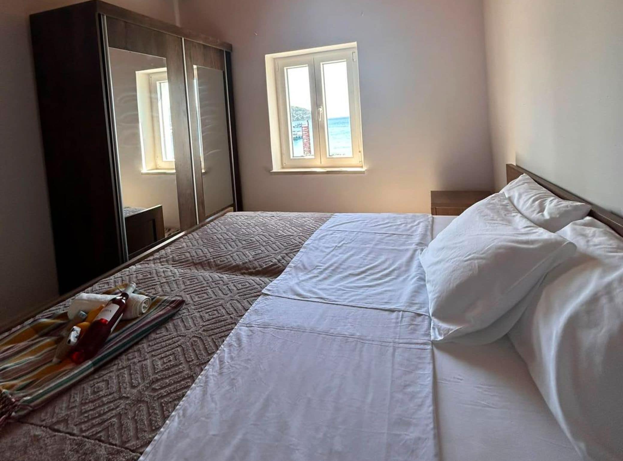 Une chambre à coucher avec un lit, une armoire, une fenêtre donnant sur un beau paysage et une table de chevet.