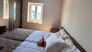 A bedroom with a bed, a window with a view of the sea, and a wardrobe.