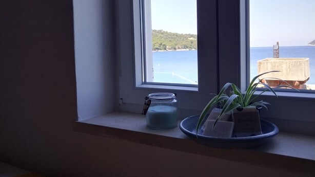 A window with a view of the sea and a distant island.