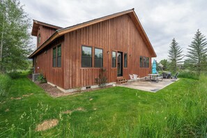Eine Holzhütte mit Terrasse, umgeben von viel Grün.