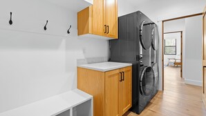 A modern kitchen with wooden cabinets, a built-in washing machine, and a white countertop.