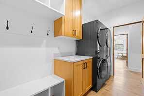 Eine moderne Küche mit Holzschränken, einer eingebauten Waschmaschine und einer weißen Arbeitsplatte.