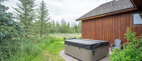 Una cabaña de madera con jacuzzi y zona de estar exterior.
