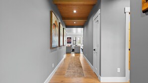 A hallway with wooden flooring, grey walls, and a ceiling with wooden beams.