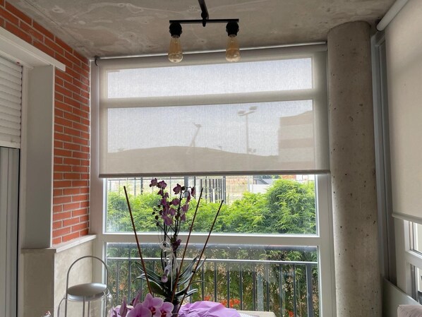 Una habitación con un ventanal grande, una silla y una planta.