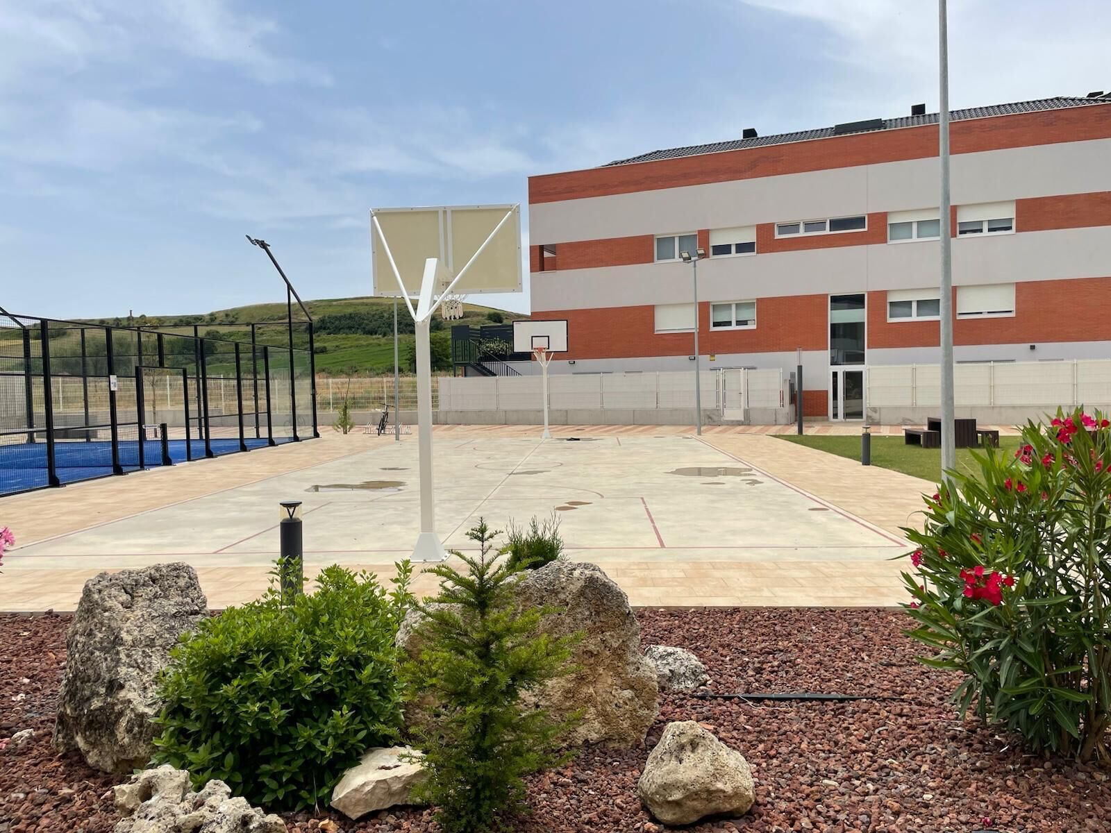 An outdoor basketball court with a building in the background.