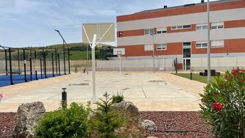 An outdoor basketball court with a building in the background.