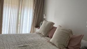 Et soveværelse med en seng, gardiner og en lampe i loftet.