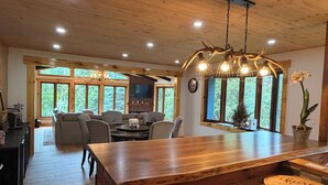 Un intérieur en bois comprenant un coin repas, une cuisine et de grandes fenêtres.