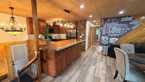 Una cocina moderna con armarios de madera, una isla central y un comedor con un mural con temática de café.