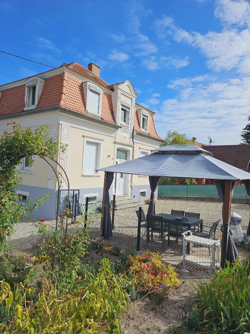 Een huis met een tuin, een terras, een pergola en een eethoek.