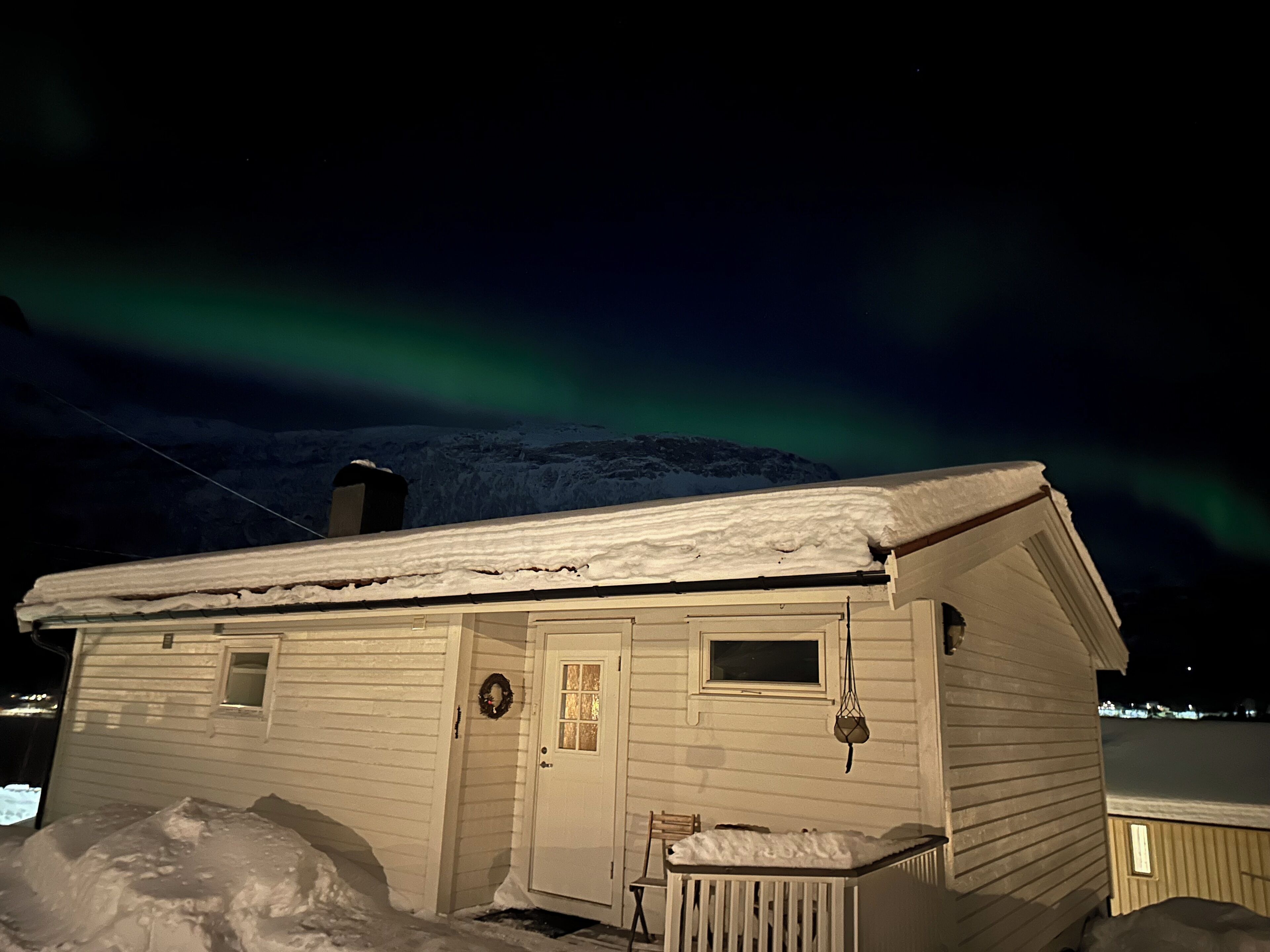 Une cabane recouverte de neige, avec une porte, des fenêtres et un petit porche.