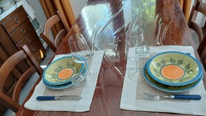 Una taula de dinar de fusta amb dues mancades de plats, gots i coberts.