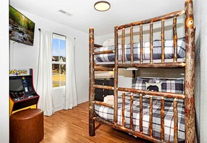 A bunk bed with a rustic design, a television, and a small stool in a room with a window and curtains. - Charming Family Retreat with Hot Tub near Dollywood in Sevierville, Tennessee (Sevierville)