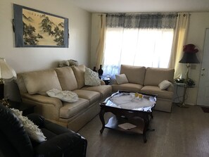 Ein Wohnzimmer mit zwei Sofas, einem Couchtisch, einer Lampe und einem Gemälde an der Wand.