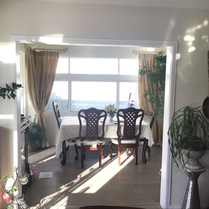 A dining area with a table and chairs, a view through a window, and potted plants. - House SFR  2-bedroom 2 Bath Free Parking Great Price and Location (San Diego)