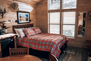 Een gezellig houten kamer met een bed, een bureau en een raam met jaloezieën.