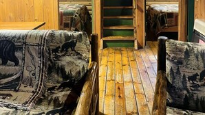 A cabin interior with a wooden staircase, two sofas with animal prints, and a sign indicating 'Cabin #5'. - Quaint Cabin Rental in Pennsylvania for Cozy Family Getaways to Cook Forest (Clarington)