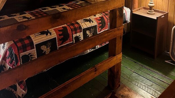A rustic attic bedroom with a bunk bed, a wooden ceiling, and a nightstand with a lamp. - Quaint Cabin Rental in Pennsylvania for Cozy Family Getaways to Cook Forest (Clarington)