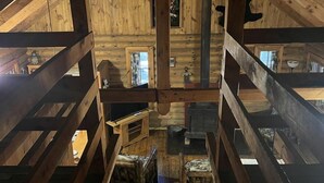 A wooden attic room with a sloped ceiling, wooden beams, and a central chimney. - Quaint Cabin Rental in Pennsylvania for Cozy Family Getaways to Cook Forest (Clarington)
