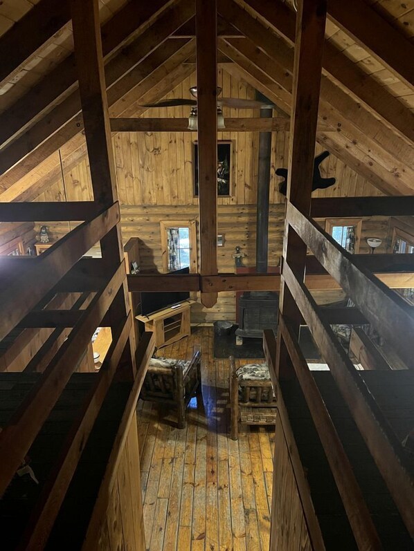 A wooden attic room with a sloped ceiling, wooden beams, and a central chimney.