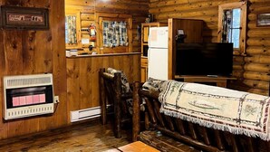 Ein Holzinnenraum mit Kamin, Fernseher und einer Bank.