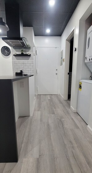 Une cuisine moderne avec un plan de travail noir, des armoires blanches, une horloge et un revêtement mural en carreaux.