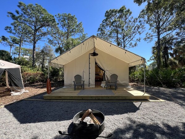 A tent with two chairs and a welcome mat in front.