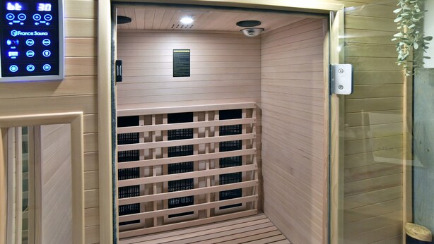Een sauna met een bedieningspaneel, houten wanden en een ventilatiesysteem.
