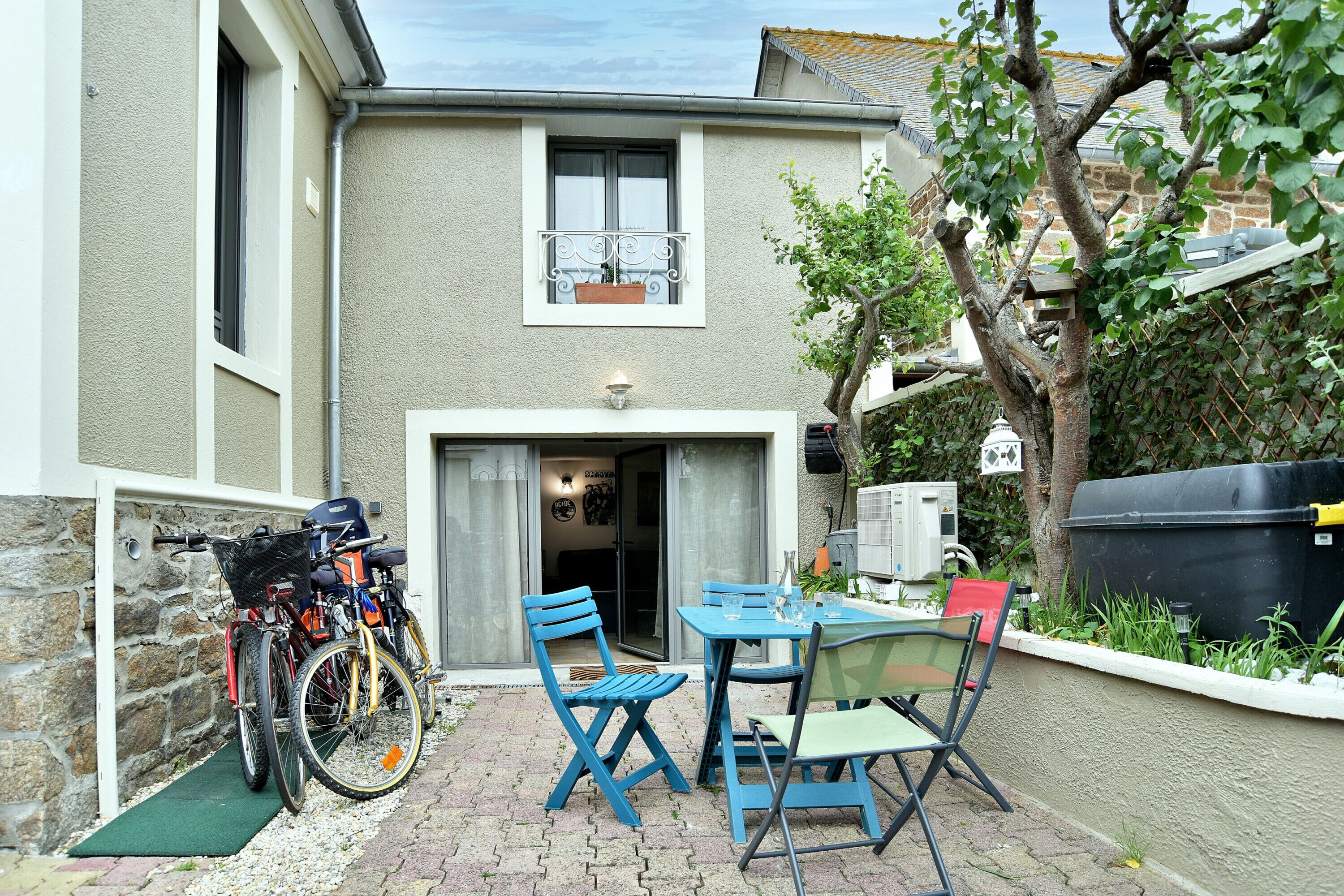 Un patio con tavolo e sedie, una bicicletta e un muro in pietra.