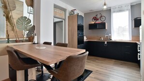 Een moderne keuken met houten kastjes, een eettafel met stoelen en een fiets aan de muur.